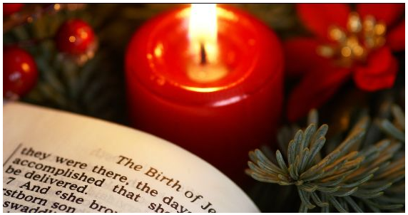 Red candle with Bible reading about the birth of Jesus